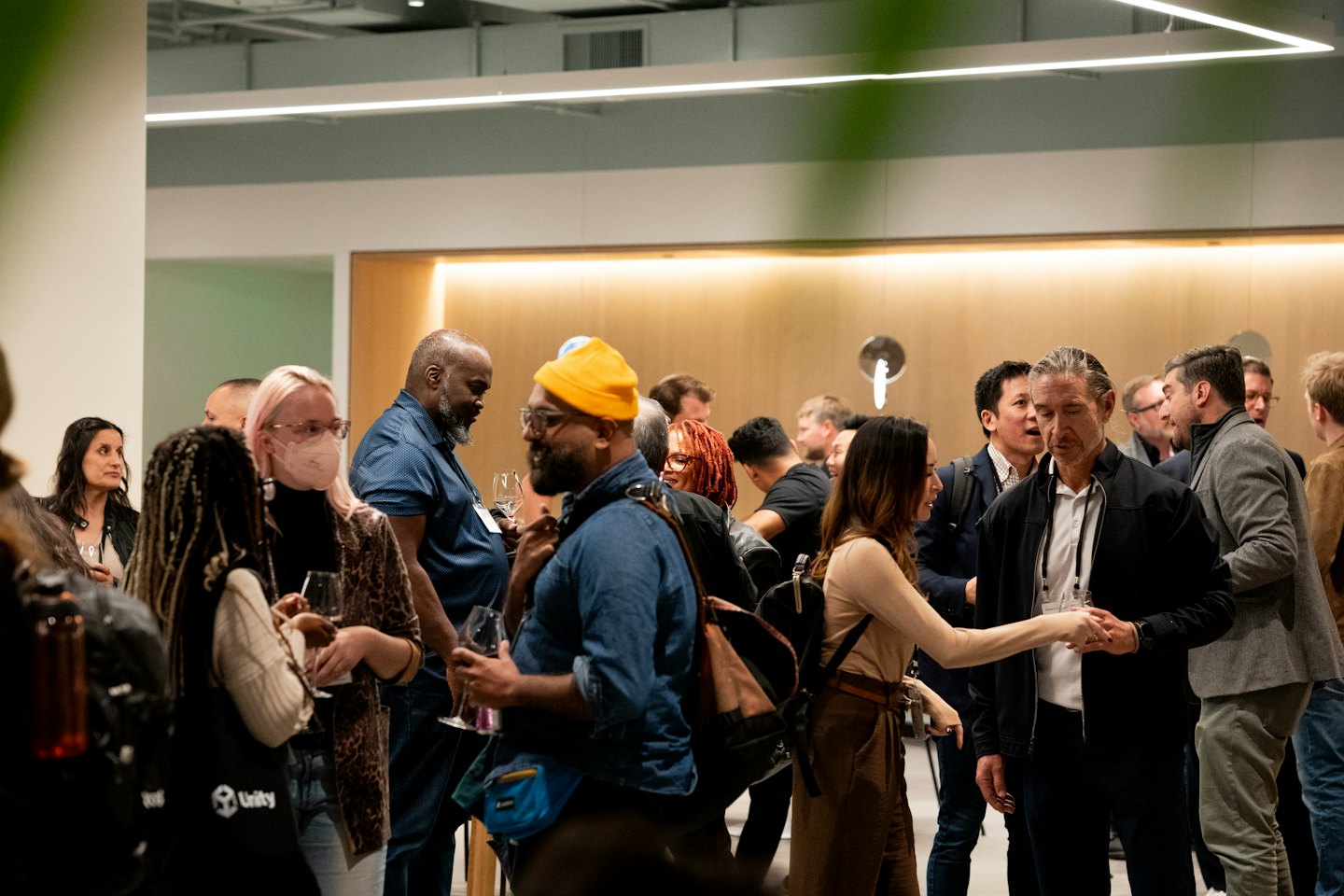 Professionisti che fanno networking e tengono bicchieri di vino a un evento al chiuso.
